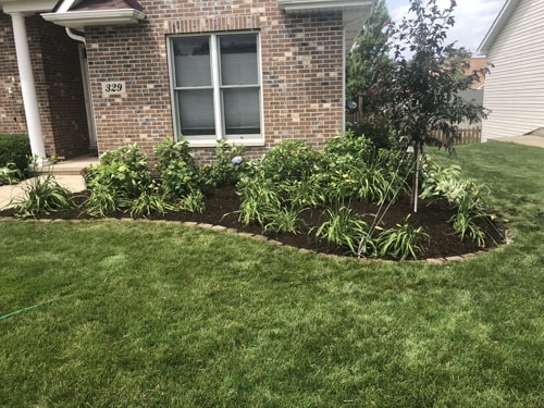 Professional garden upgrade around a front porch with mulch and blooms