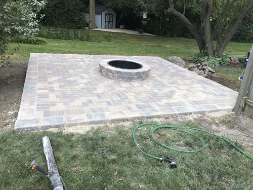 Outdoor fire pit installation in progress by landscaping crew in Harvard IL